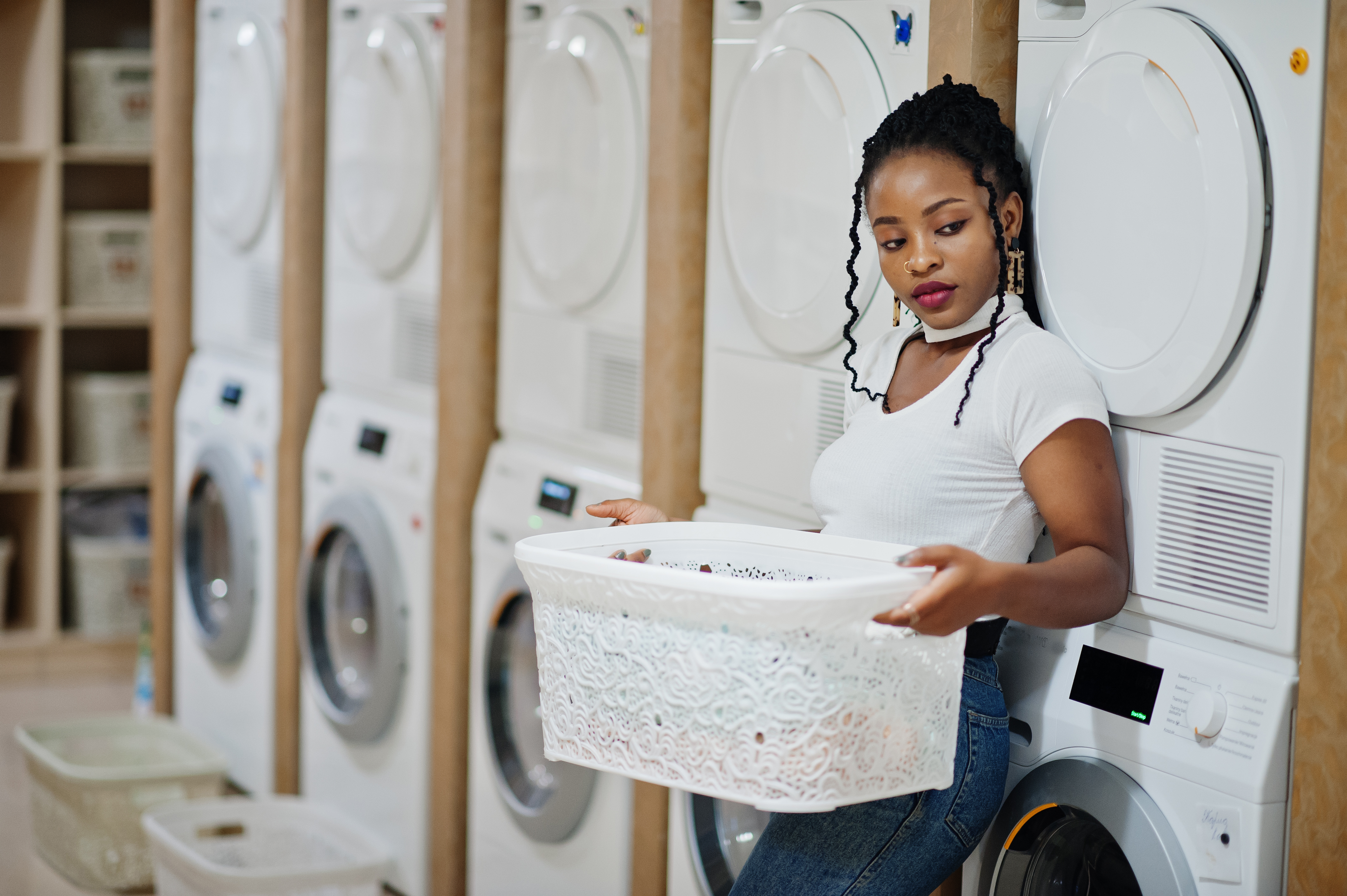 Home cheerful african american woman with white basket near washing m